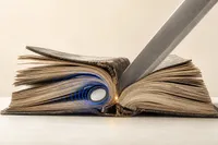 Un libro antiguo abierto con un AirTag emitiendo ondas de ubicación justo en el punto donde una cuchilla corta el lomo