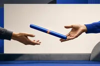 Dos manos abiertas entregándose un testigo de relevo azul cobalto con una franja ámbar, frente a un panel rectangular claro y vacío.