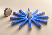Una rueda de radios azul cobalto cuyo centro lo ocupa ahora una pequeña placa rectangular vertical, mientras la vieja pieza redonda del eje descansa de lado fuera de la rueda