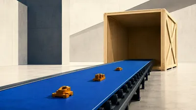 Una cinta transportadora azul cobalto que lleva apenas tres piezas ámbar hacia un enorme cajón de embalaje de madera vacío