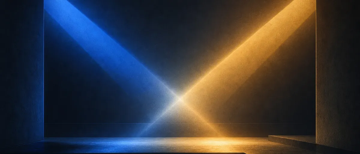 Dos haces de luz que se cruzan sobre un escenario en penumbra: uno cobalto que se atenúa, otro ámbar que asciende, sin figuras ni rostros.